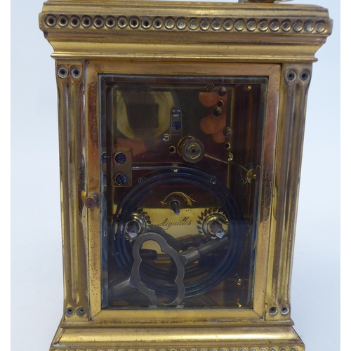 158 - An early 20thC lacquered brass cased carriage clock with reeded corner pillars and scrolled friezes,... 