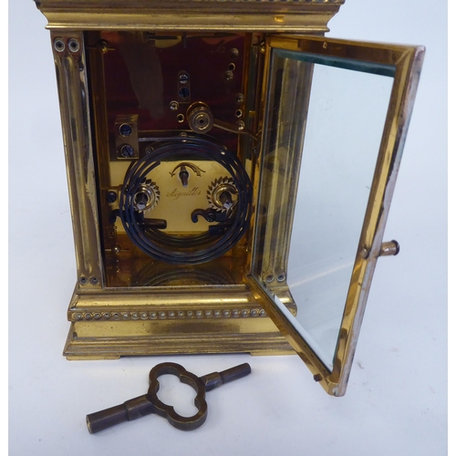 158 - An early 20thC lacquered brass cased carriage clock with reeded corner pillars and scrolled friezes,... 