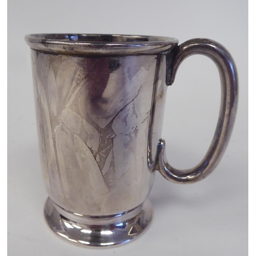 183 - A silver Christening mug with a rolled rim and hollow C-scrolled handle, on a splayed footrim  ... 