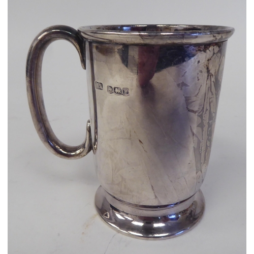 183 - A silver Christening mug with a rolled rim and hollow C-scrolled handle, on a splayed footrim  ... 