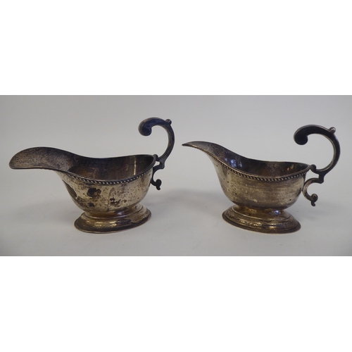 188 - A pair of silver oval sauce boats, each with a gadrooned rim and hollow, double C-scrolled handle, o... 