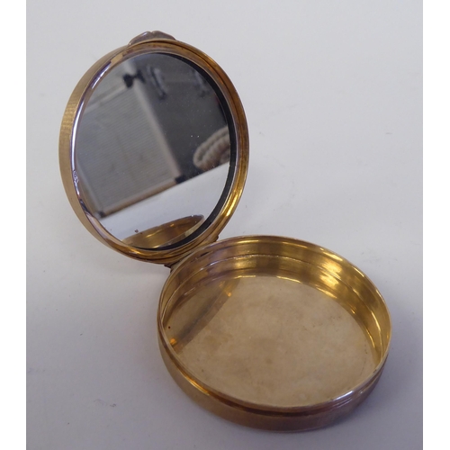 190 - A 9ct gold engine turned and blue enamel, circular powder compact with a hinged lid and inset vanity... 