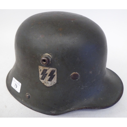 79 - A German Great War military, steel helmet used by the SS in World War II with a hide liner and two d... 