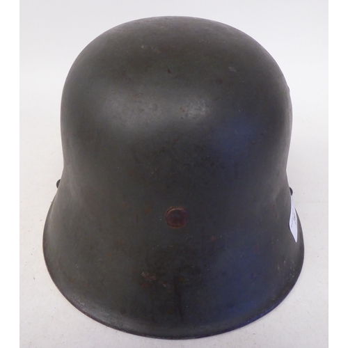 79 - A German Great War military, steel helmet used by the SS in World War II with a hide liner and two d... 