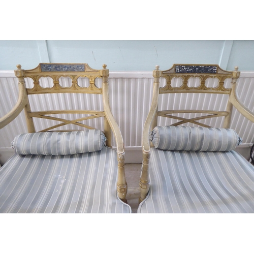 83 - A pair of early 20thC Regency inspired, cream painted and gilded elbow chairs with low, curved backs... 