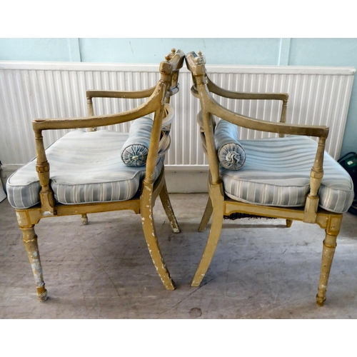 83 - A pair of early 20thC Regency inspired, cream painted and gilded elbow chairs with low, curved backs... 