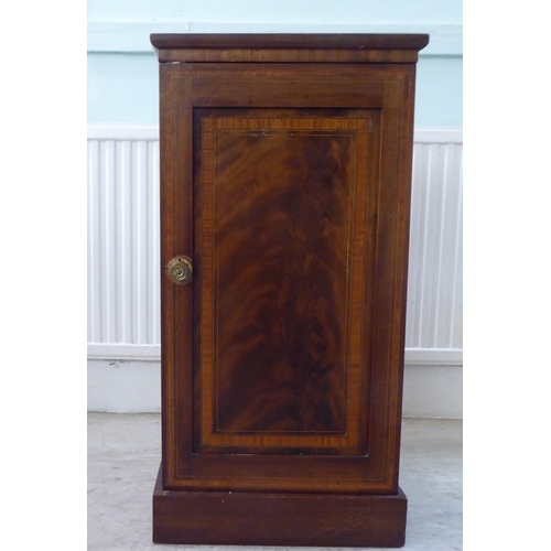 93 - A late Victorian crossbanded and string inlaid mahogany pot cupboard, enclosed by a full-height pane... 