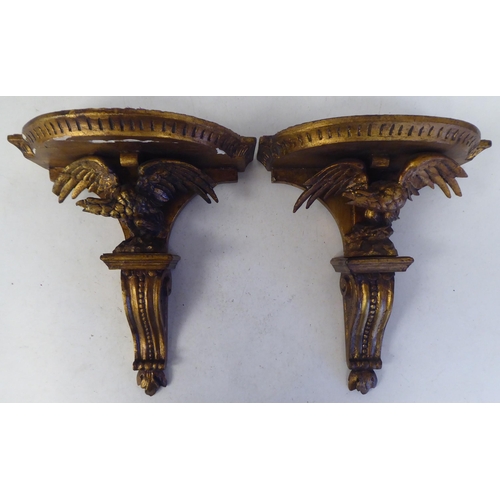 97 - A pair of late 19thC carved wooden and gilt gesso moulded wall brackets, each featuring a semi-circu... 