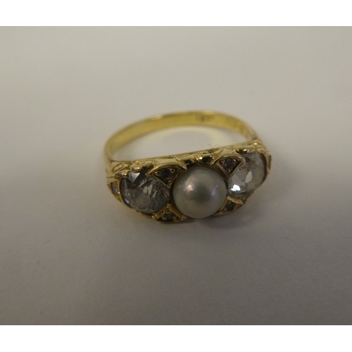 100 - A gold coloured metal ring with a scrolled shank, rubover set with two diamonds and a single pearl  ... 