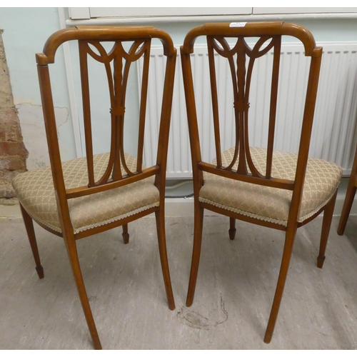 18 - A pair of Edwardian (possibly Maple & Co) ebony inlaid satinwood framed salon chairs with garlan... 