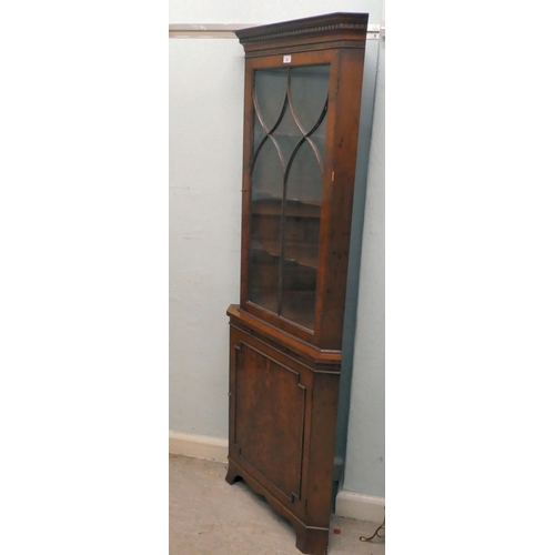 20 - A modern yewwood corner cabinet with a glazed, panelled door, raised on bracket feet  75