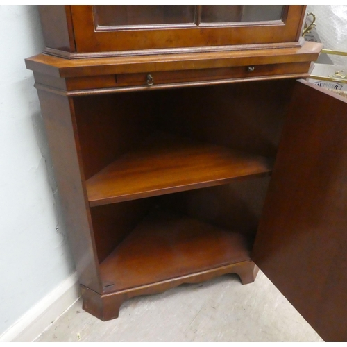 20 - A modern yewwood corner cabinet with a glazed, panelled door, raised on bracket feet  75