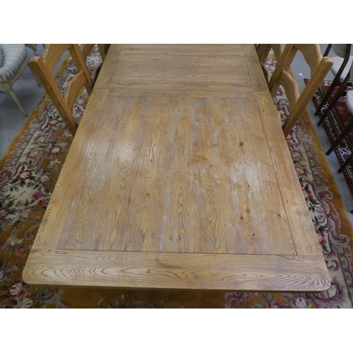 273 - A modern light oak dining table, the top with rounded corners, raised on turned pedestals and block ... 