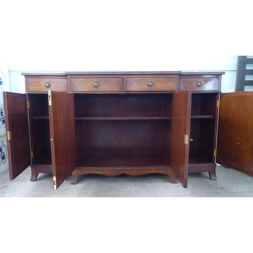 73 - A modern crossbanded walnut and walnut veneered breakfront sideboard with four frieze drawers, over ... 