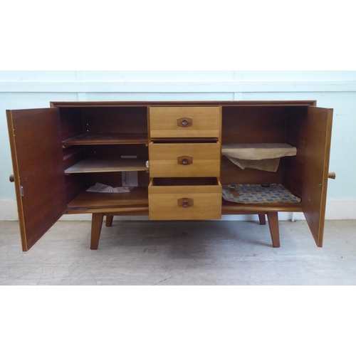 84 - A 1970s two-tone teak inverted breakfront sideboard with a bank of three central drawers, flanked by... 