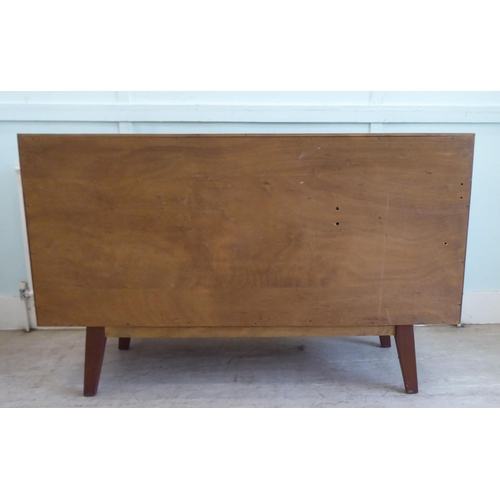 84 - A 1970s two-tone teak inverted breakfront sideboard with a bank of three central drawers, flanked by... 