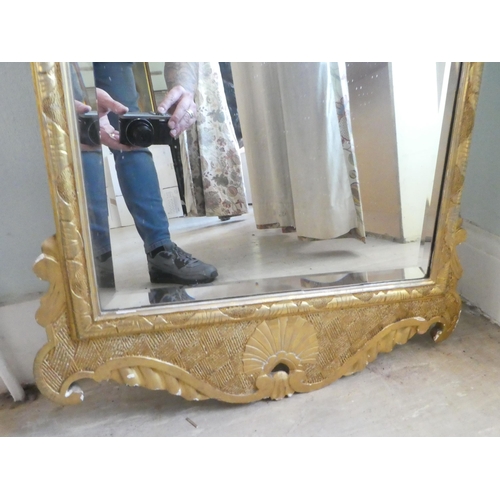 61 - An early 20thC mirror, the shaped, bevelled plate set in a gilded pine frame  44