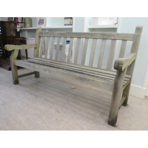 64 - A slatted weathered teak garden bench, raised on square legs  70