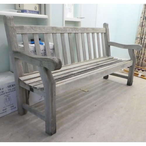 64 - A slatted weathered teak garden bench, raised on square legs  70