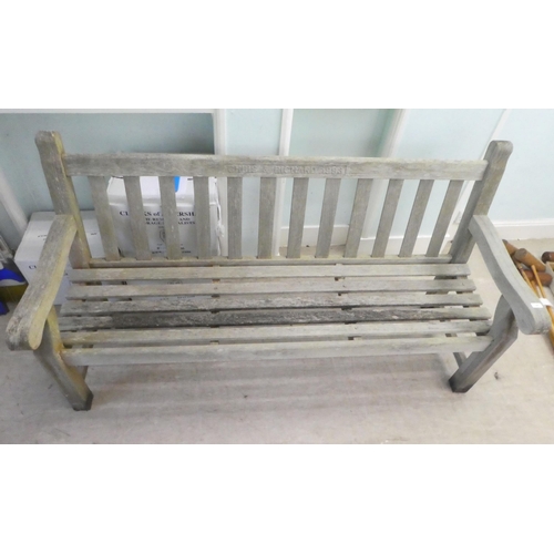 64 - A slatted weathered teak garden bench, raised on square legs  70