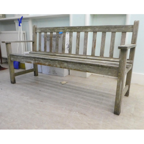 65 - A slatted weathered teak garden bench, raised on square legs  60