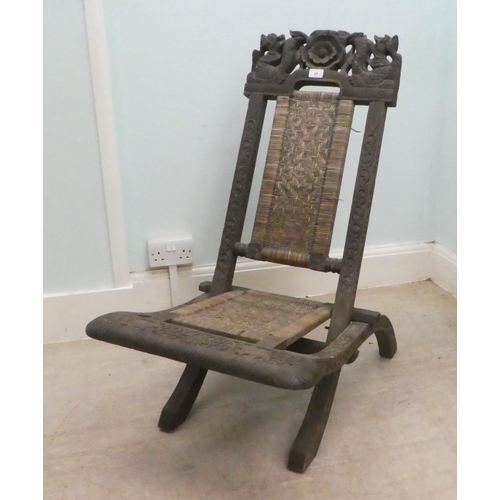 66 - An early/mid 20thC Burmese carved hardwood and wicker panelled folding veranda chair 