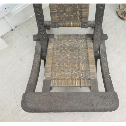 66 - An early/mid 20thC Burmese carved hardwood and wicker panelled folding veranda chair 