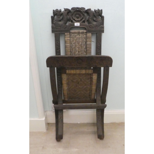 66 - An early/mid 20thC Burmese carved hardwood and wicker panelled folding veranda chair 