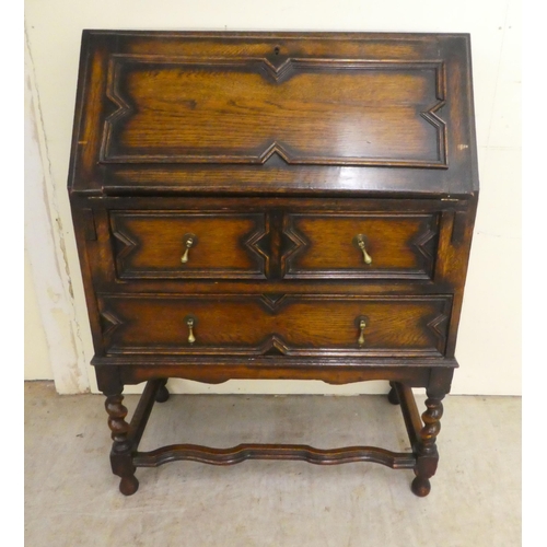 73 - A 1930s oak bureau, the fall flap over two long drawers, raised on barleytwist, block supports ... 