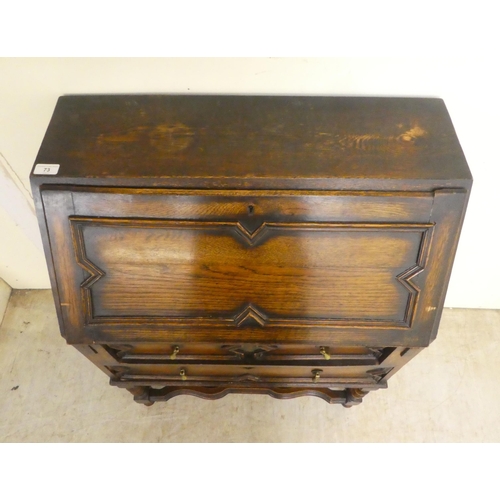 73 - A 1930s oak bureau, the fall flap over two long drawers, raised on barleytwist, block supports ... 