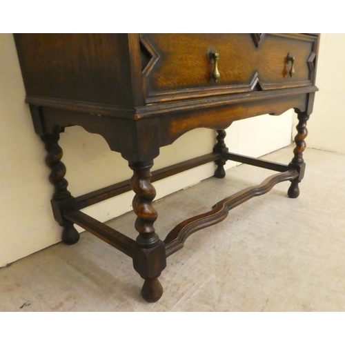 73 - A 1930s oak bureau, the fall flap over two long drawers, raised on barleytwist, block supports ... 