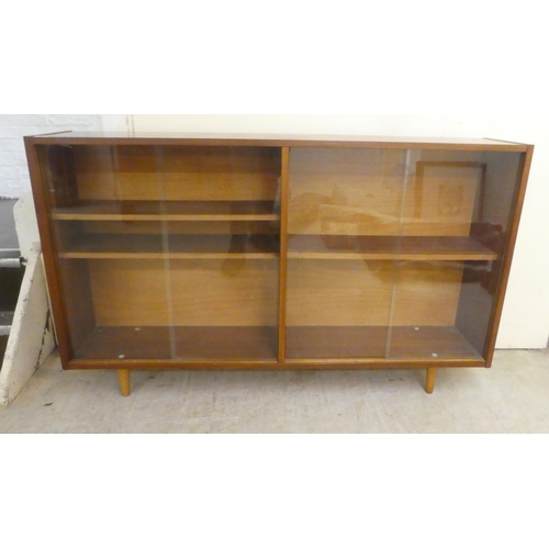 76 - A 1970s teak, glazed front bookcase, raised on tapered legs  32