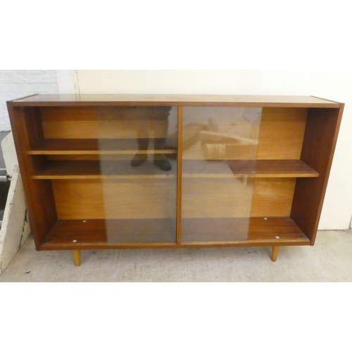 76 - A 1970s teak, glazed front bookcase, raised on tapered legs  32