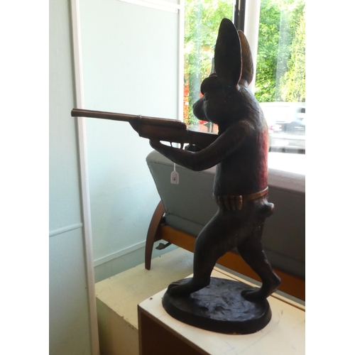 78 - A cast bronze model, a hunting hare holding a double barrel shotgun  36