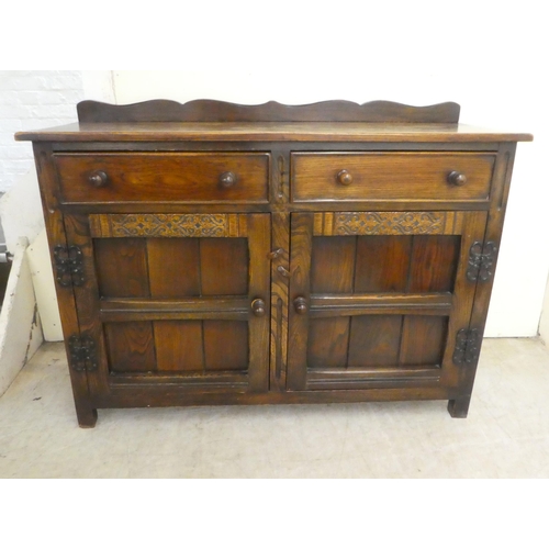 84 - A 20thC Old English style oak dresser with two frieze drawers, over two panelled doors, raised on bl... 