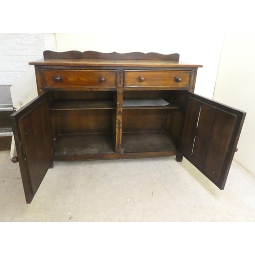 84 - A 20thC Old English style oak dresser with two frieze drawers, over two panelled doors, raised on bl... 