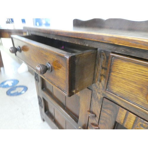 84 - A 20thC Old English style oak dresser with two frieze drawers, over two panelled doors, raised on bl... 