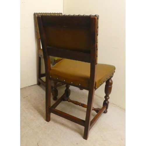 87 - A set of four 20thC Old English style oak and stained beech framed dining chairs with stud upholster... 