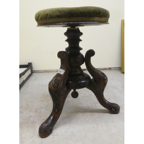 88 - A 20thC music stool, the green part button upholstered top on a carved hardwood tripod base