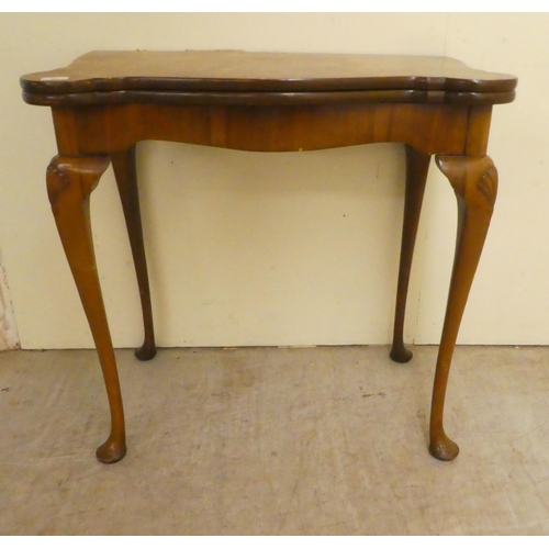 91 - A mid 20thC Queen Anne style quarter walnut veneered card table, the hinged top over slender legs an... 