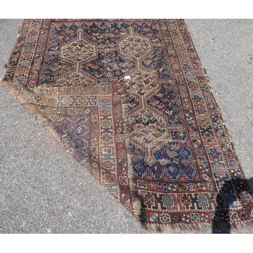 14 - A Persian rug, decorated with six hexagonal motifs, bordered by repeating stylised designs, on a mul... 