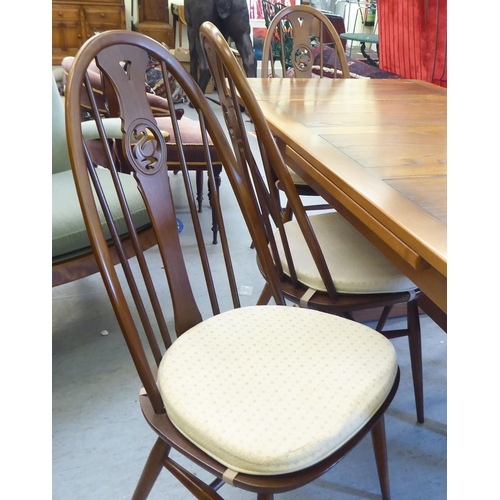 153 - An Ercol Golden Dawn beech and elm draw leaf dining table with a panelled top, raised on shaped tres... 