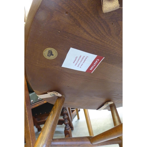 153 - An Ercol Golden Dawn beech and elm draw leaf dining table with a panelled top, raised on shaped tres... 