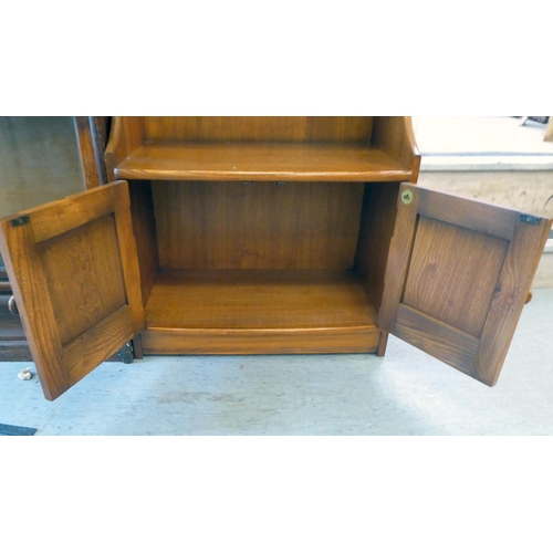 158 - An Ercol Golden Dawn beech and elm waterfall front, two tier bookcase, over a pair of panelled doors... 