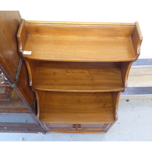 158 - An Ercol Golden Dawn beech and elm waterfall front, two tier bookcase, over a pair of panelled doors... 