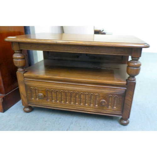 159 - An Ercol Golden Dawn beech and elm television stand, the top with a triangular fall flap, over an op... 