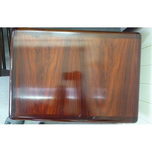 17 - A nesting set of three modern rosewood finished occasional tables with panelled tops, raised on cham... 