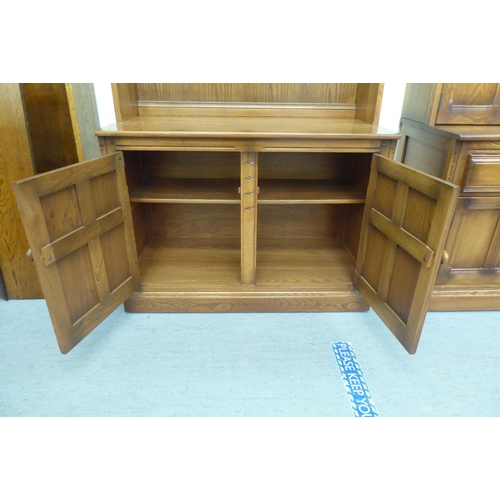 173 - An Ercol Golden Dawn beech and elm livingroom unit, the upper part enclosed by a pair of bevelled gl... 