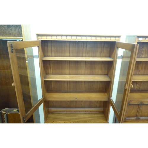 173 - An Ercol Golden Dawn beech and elm livingroom unit, the upper part enclosed by a pair of bevelled gl... 