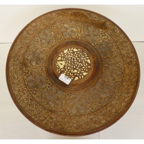 176 - An Indian carved teak side table with an inlaid bone central motif, raised on elephants' head suppor... 